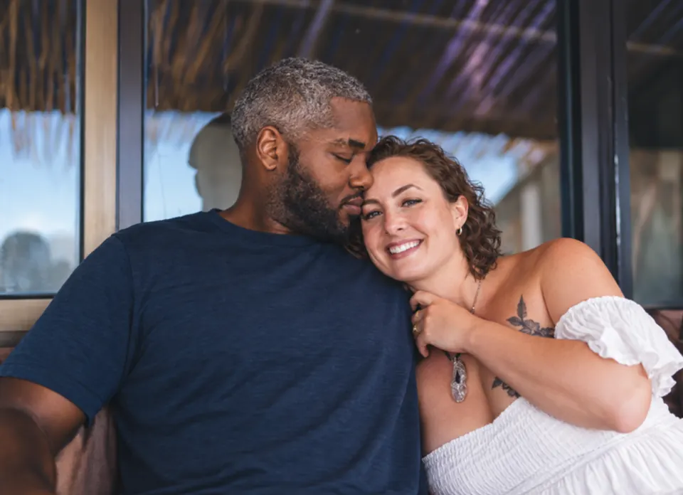 A grey-haired man and a woman with short brown curls sharing a warm hug